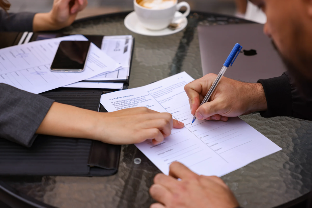 Real estate agent reviewing a deposit agreement with foreign buyers in Georgia during the Tbilisi property market real estate process overview, highlighting real estate due diligence, contract conditions, and buyer protection steps.