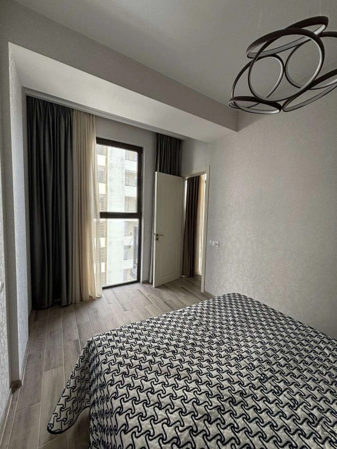 2-room apartment for rent on Chqondideli Street, Nadzaladevi, Tbilisi — bedroom with floor-to-ceiling window and blackout curtains