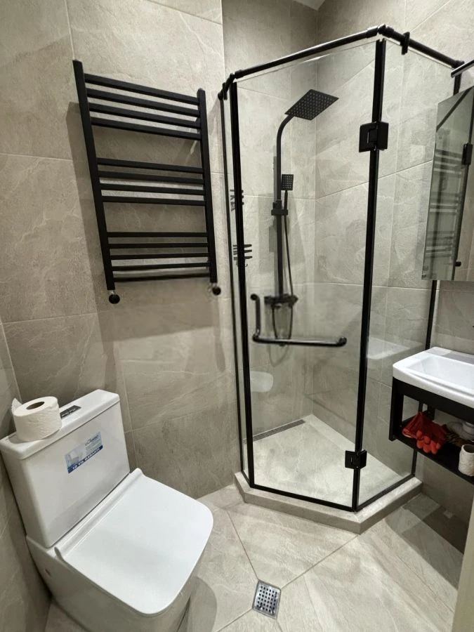 2-room apartment for rent on Chqondideli Street, Nadzaladevi, Tbilisi — bathroom with black-frame corner shower, towel radiator and vanity