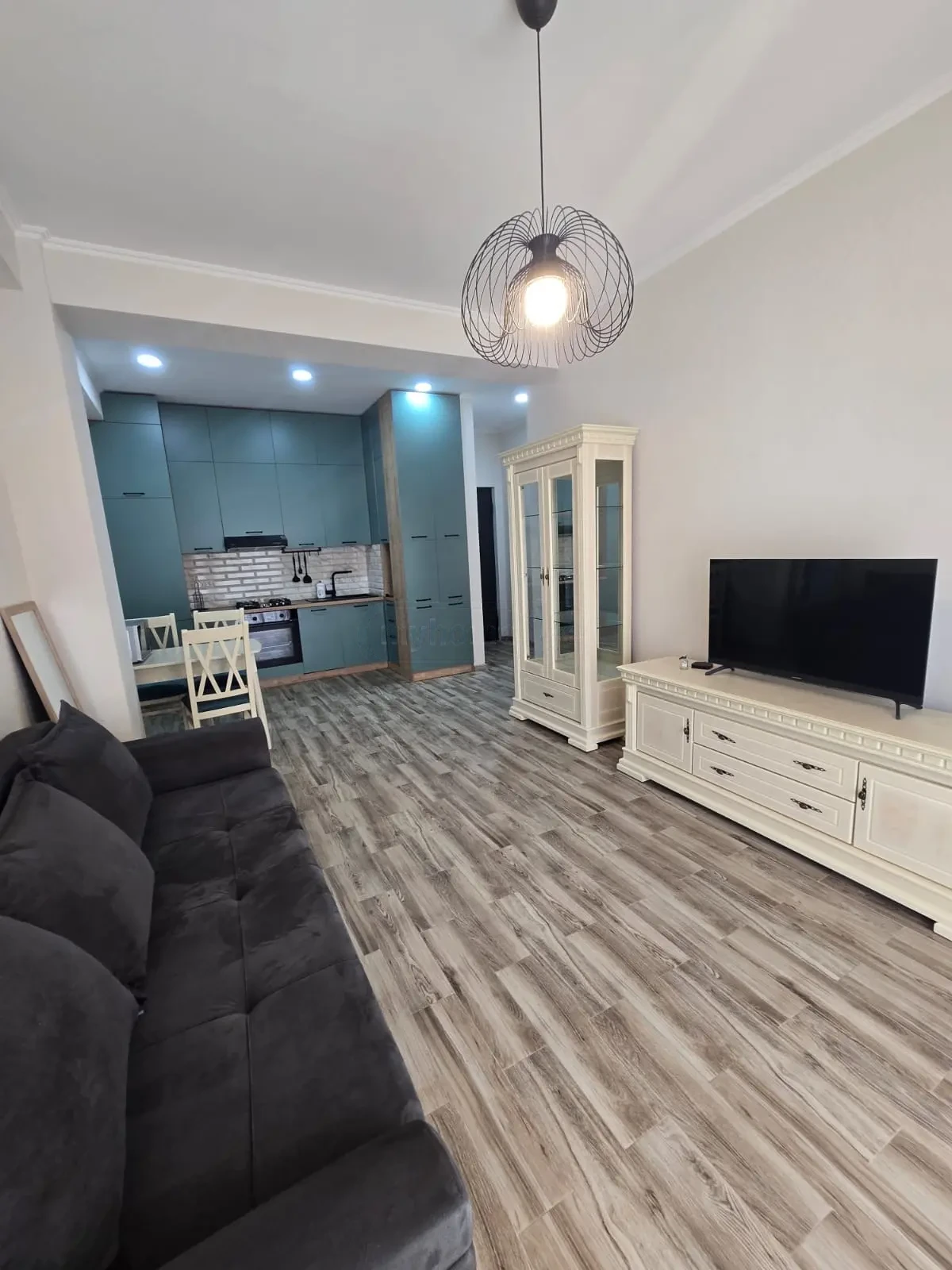 2-room furnished apartment for sale on Mindeli Street 9b, Saburtalo, Tbilisi — living room with sofa and teal kitchen