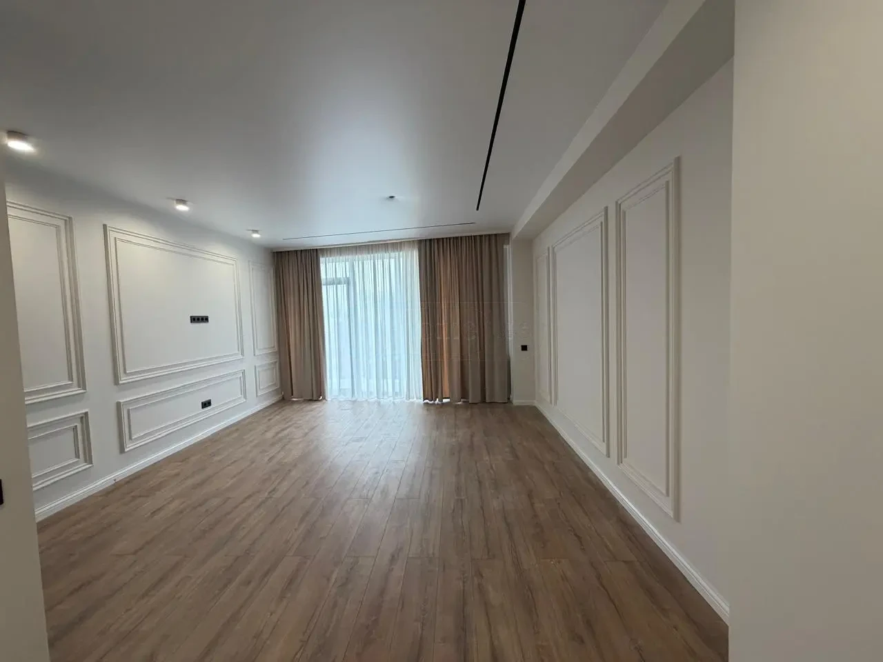 2-room apartment for sale on Politkovskaya Street 40a, Saburtalo, Tbilisi — living room with TV wall and floor-to-ceiling curtains