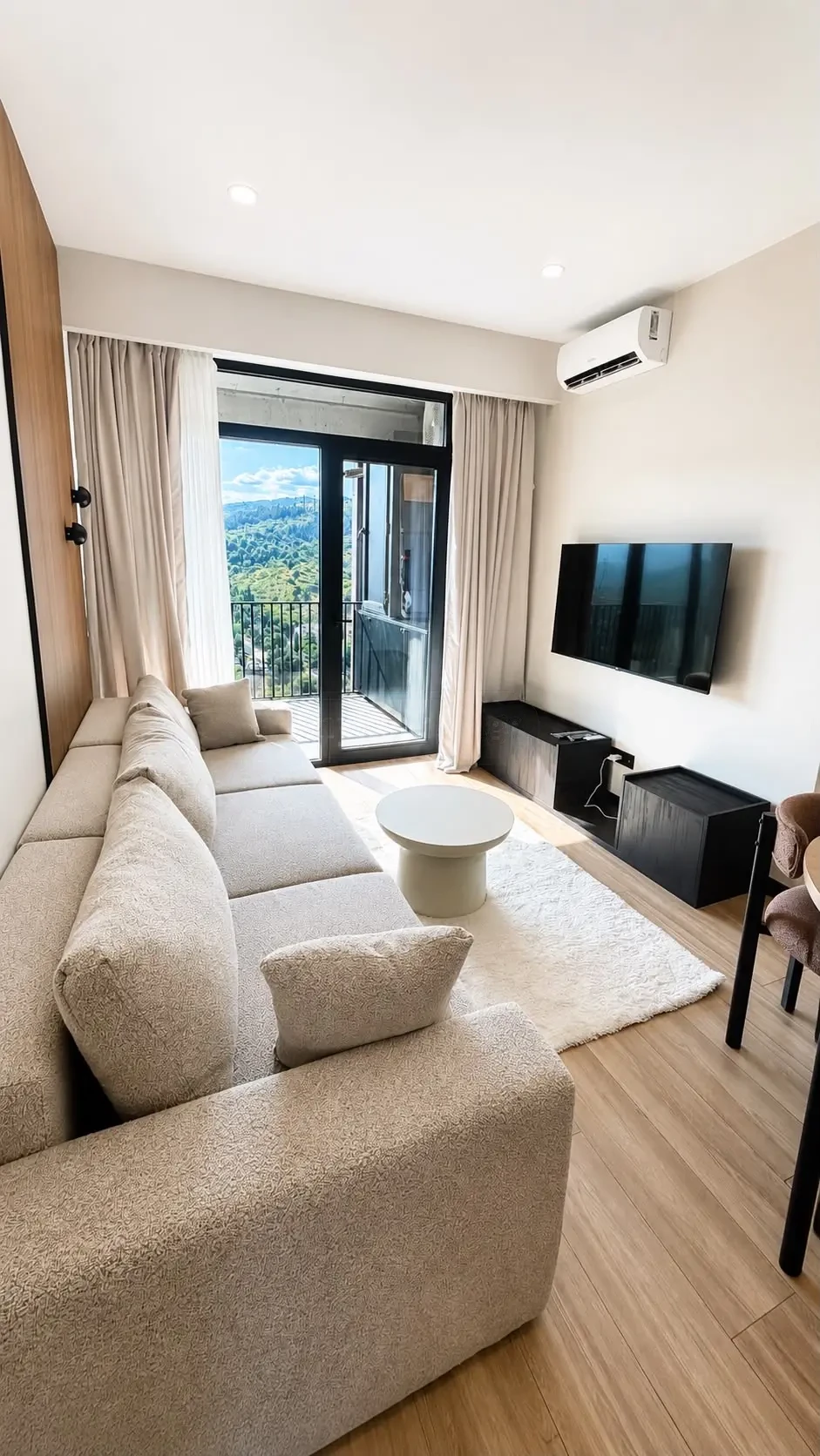 2-room furnished apartment for sale on Politkovskaya Street 46, 16th floor, Saburtalo, Tbilisi — living room with sofa, TV and hill-view balcony door