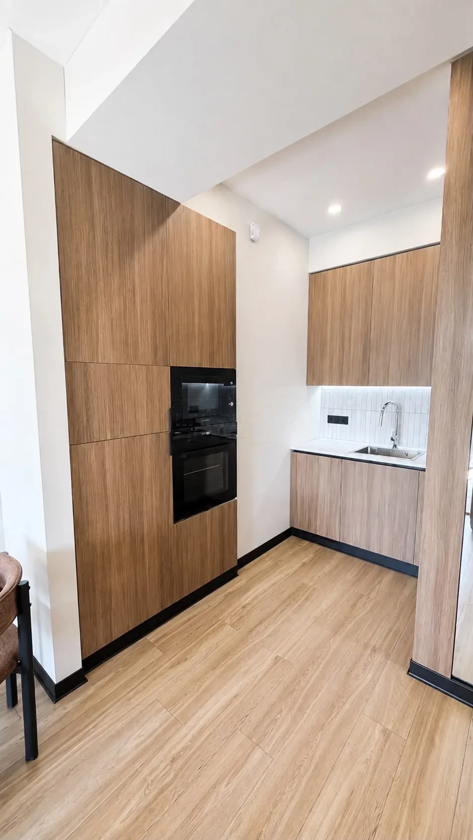 2-room furnished apartment for sale on Politkovskaya Street 46, 16th floor, Saburtalo, Tbilisi — kitchen with tall wood cabinetry and built-in oven
