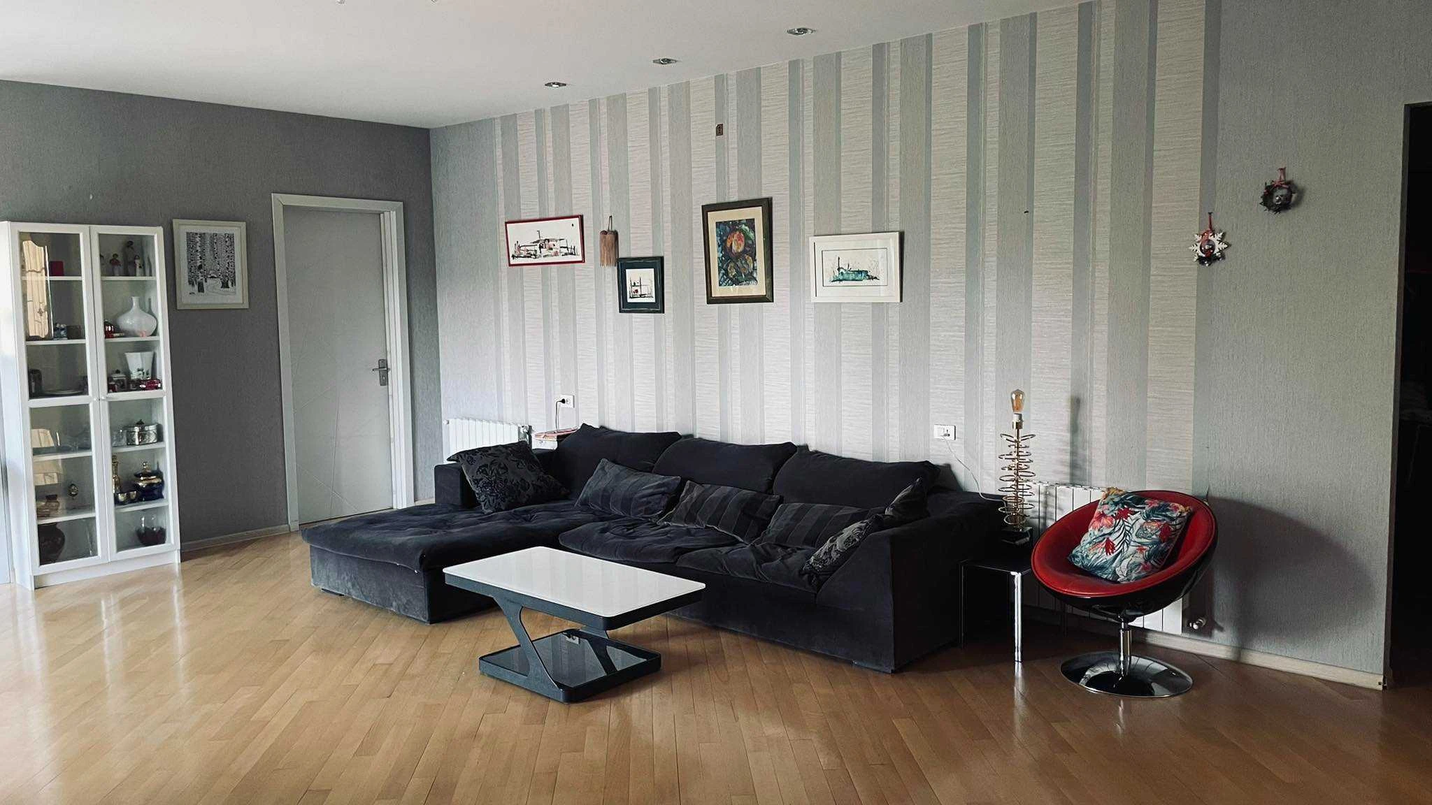 4-room apartment for rent on Titsian Tabidze Street 61, Vake, Tbilisi — living room with sectional sofa and display cabinet