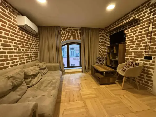 1-room apartment for rent on Gorki Street, Chugureti, Tbilisi — living room with exposed brick wall and sofa